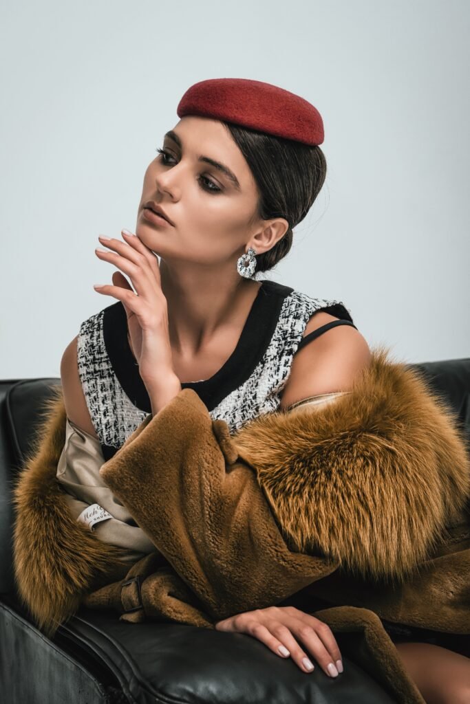 Stylish woman posing indoors with a red beret and fur coat, exuding elegance.