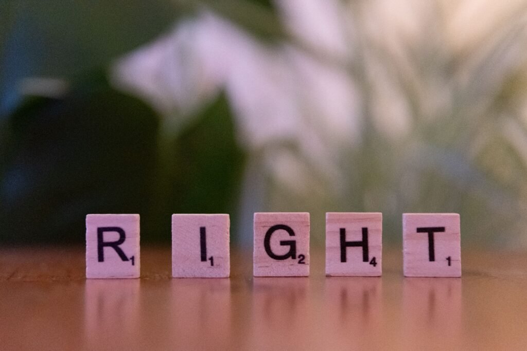 Wooden Scrabble tiles spelling 'Right' on a wooden surface with blurred background.