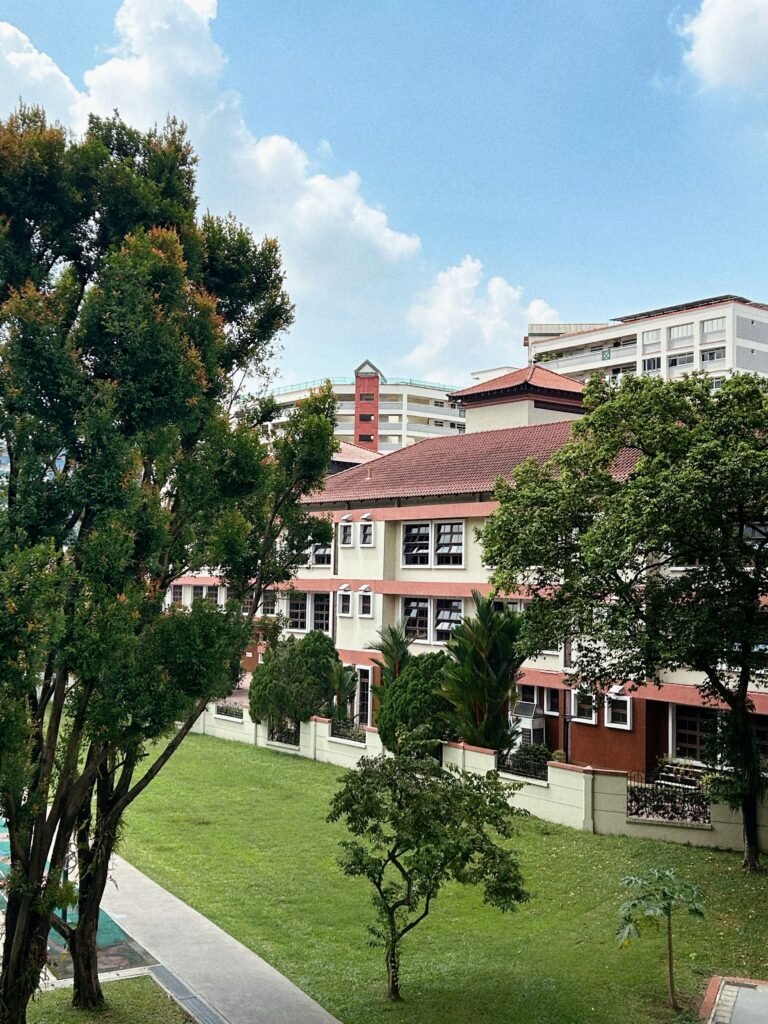 A vibrant urban residential complex surrounded by lush greenery under a bright blue sky.