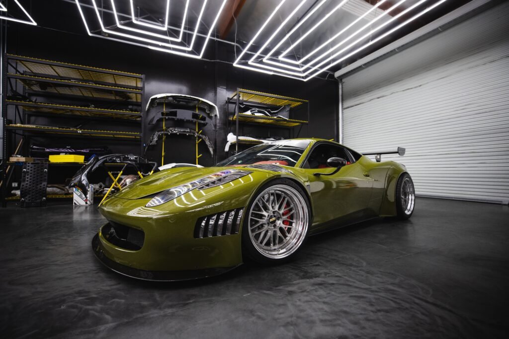 A sleek green sports car with custom modifications in a modern garage workshop.