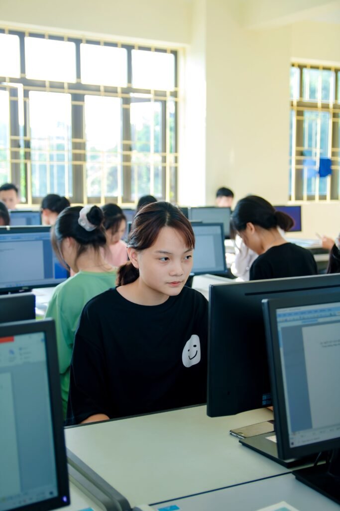 Students focused on computers in a bright classroom setting.