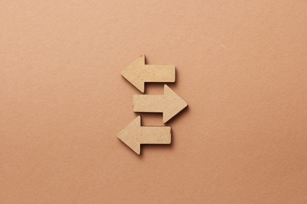 Close-up of three wooden arrows pointing in opposite directions on a beige surface.
